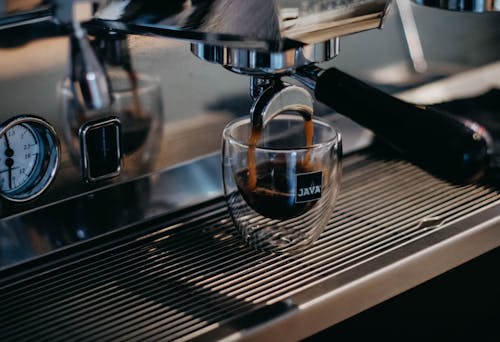 Free Modern professional coffee machine pouring freshly brewed aromatic ristretto into small glass cup in coffee shop Stock Photo