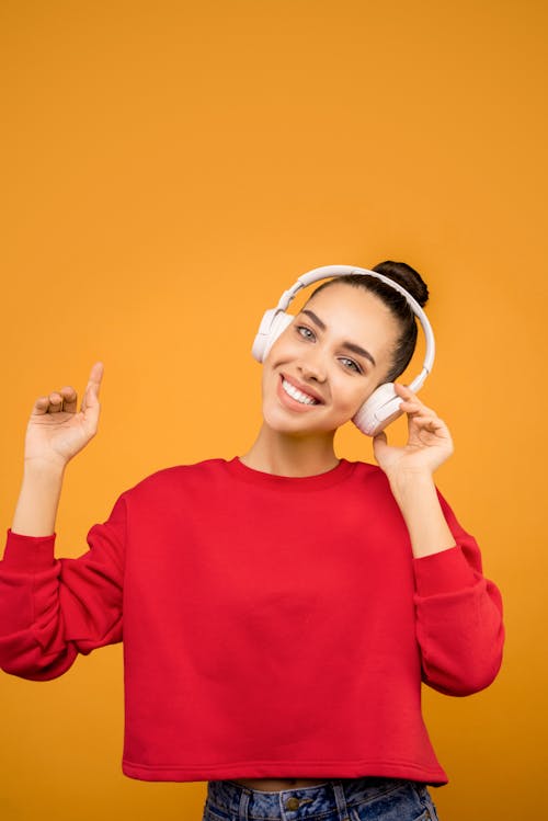 Free Woman in Red Sweater Wearing White Headphones Stock Photo