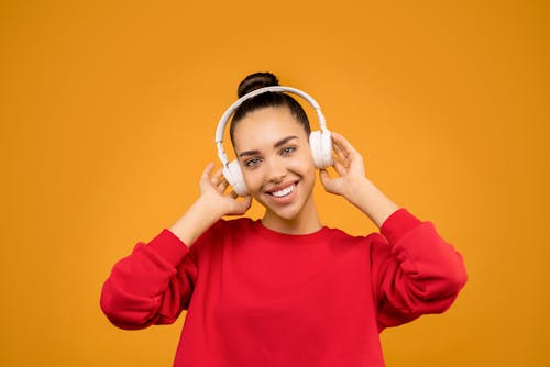 Woman in Red Sweater Wearing White Headphones