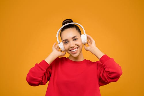 Wanita Berkerudung Merah Mengenakan Headphone Putih