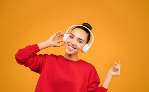 Woman in Red Sweater Wearing White Headphones