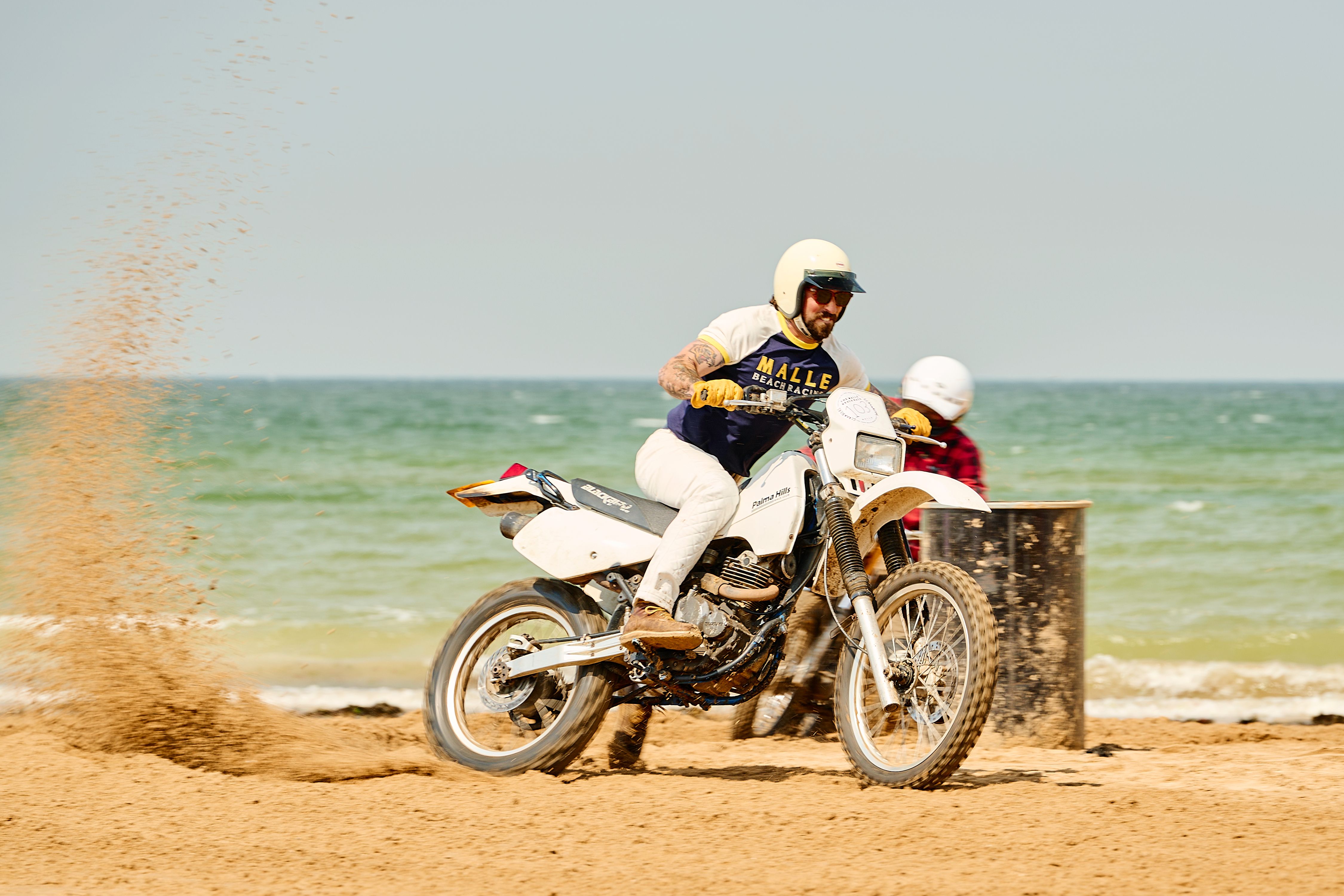 A thrilling motorcycle race on Margate beach with riders kicking up sand under a clear sky.