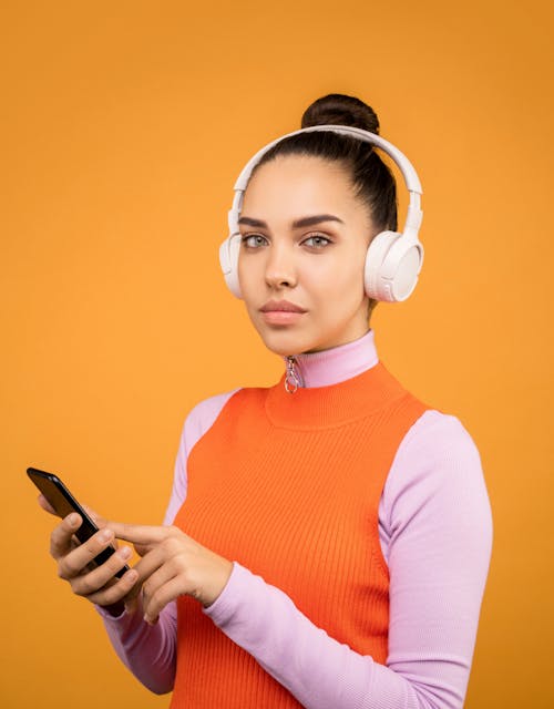 Woman in Orange and Pink Turtle Neck Shirt Holding Black Smartphone