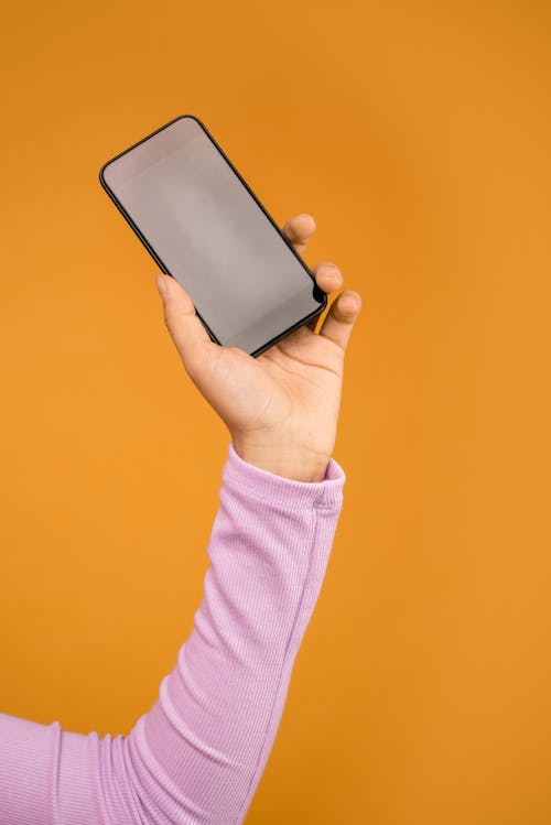 Persona Sosteniendo Smartphone Negro En Fondo Naranja