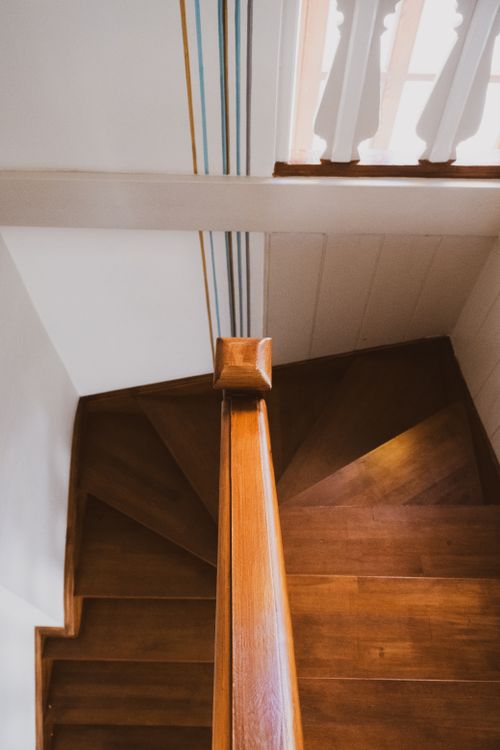 Free A stylish wooden staircase with artistic design and striped wall details, captured in natural light. Stock Photo