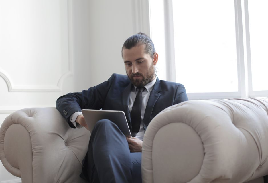 A person in a modern apartment is sitting on a sofa, looking at a tablet, and meticulously cataloging their personal belongings for an insurance inventory. - renters insurance with earthquake coverage A person in a modern apartment is sitting on a sofa, looking at a tablet, and meticulously cataloging their personal belongings for an insurance inventory. - renters insurance with earthquake coverage