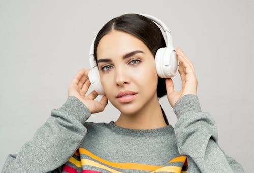 Woman in Gray and Yellow Sweater Holding White Headphones