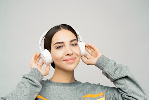 Mujer En Suéter De Rayas Grises Y Amarillas Con Auriculares Blancos