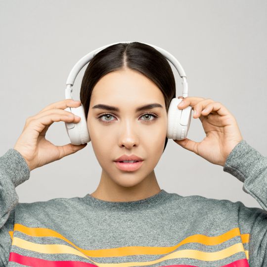 Listener adjusting a pair of white over-ear headphones — Sound On on Pexels