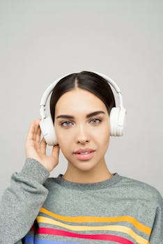 Portrait of a woman in a gray sweater with headphones enjoying music.