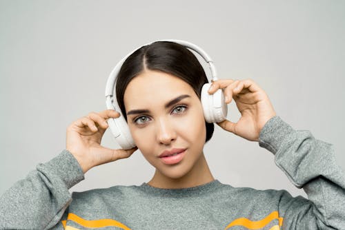 Woman in Gray Sweater Holding White Headphones