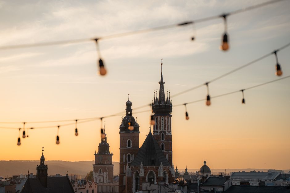 Stunning view of St. Mary's Basilica in Kraków, Poland at sunset with hanging lights.