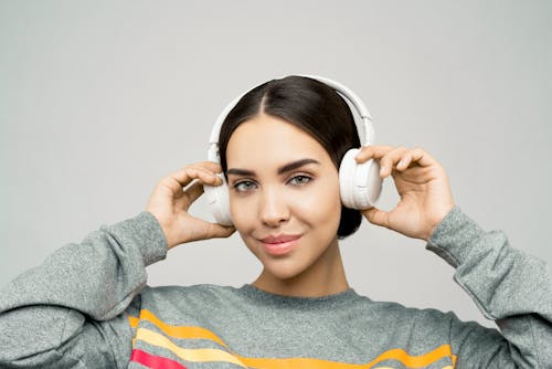 Photo of Woman In Gray Sweater Wearing White Headphones