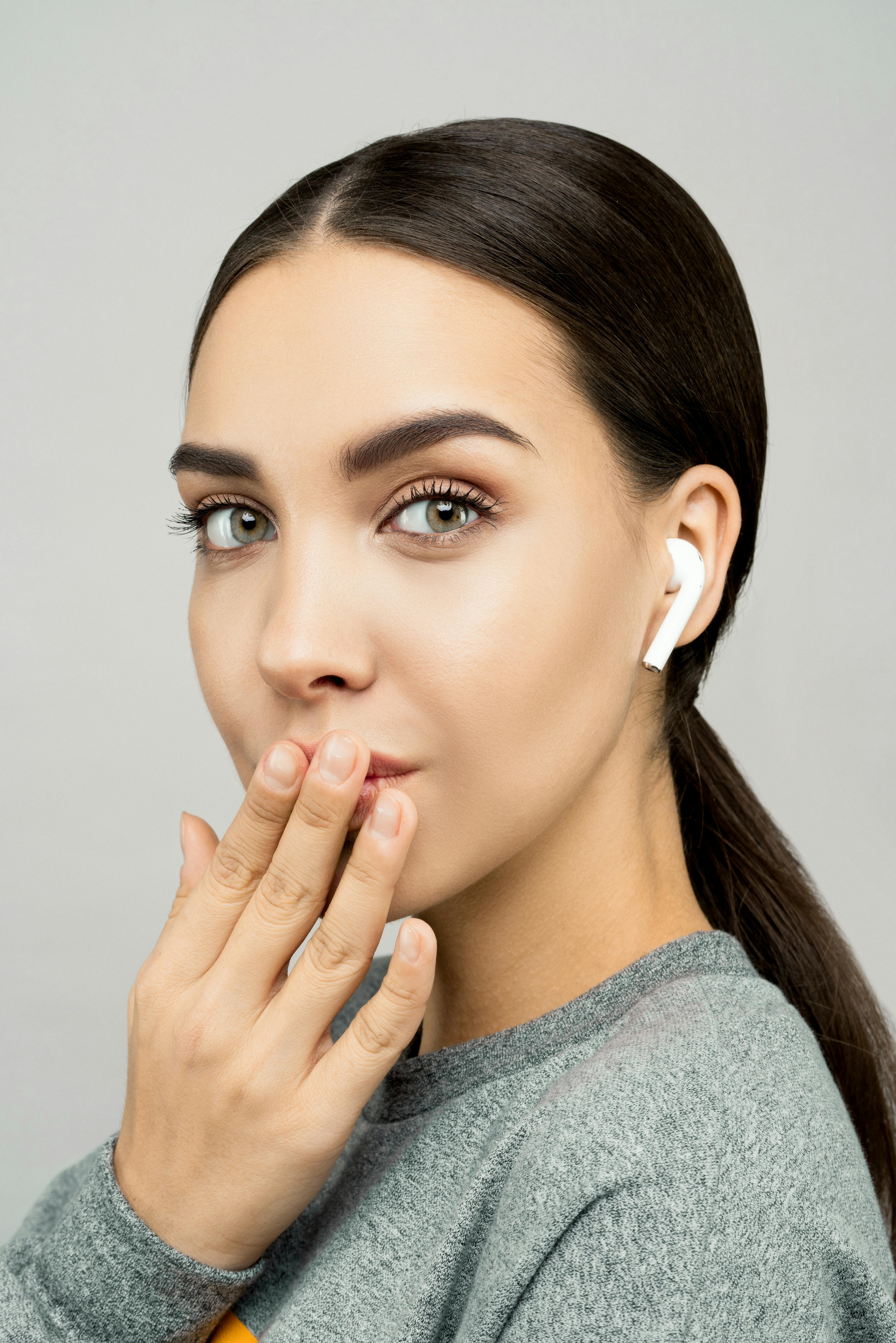 一位时尚女性在室内，穿着灰色毛衣，戴着无线耳塞的肖像