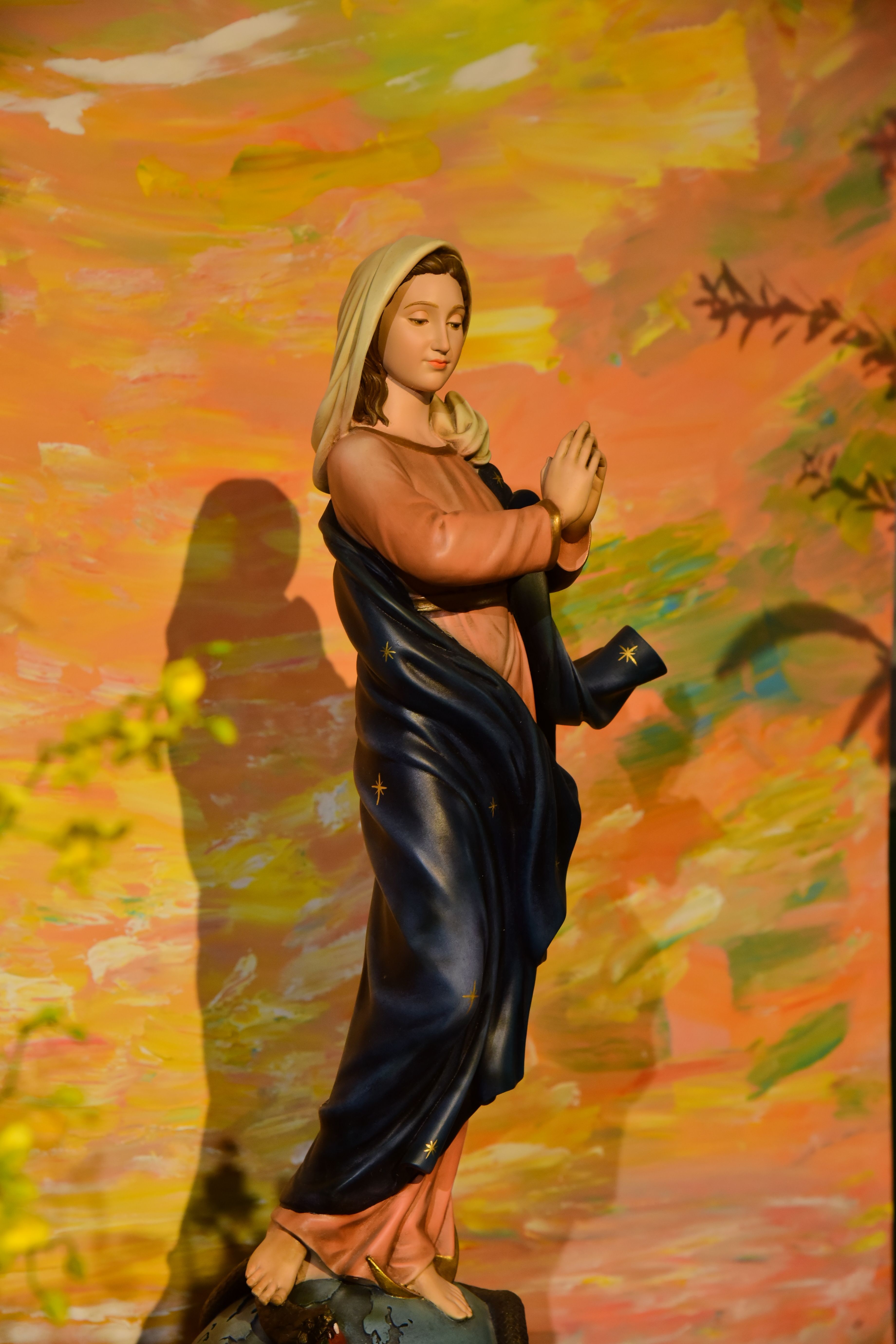 Statue of the Virgin Mary against a vibrant painted backdrop, capturing spiritual elegance.