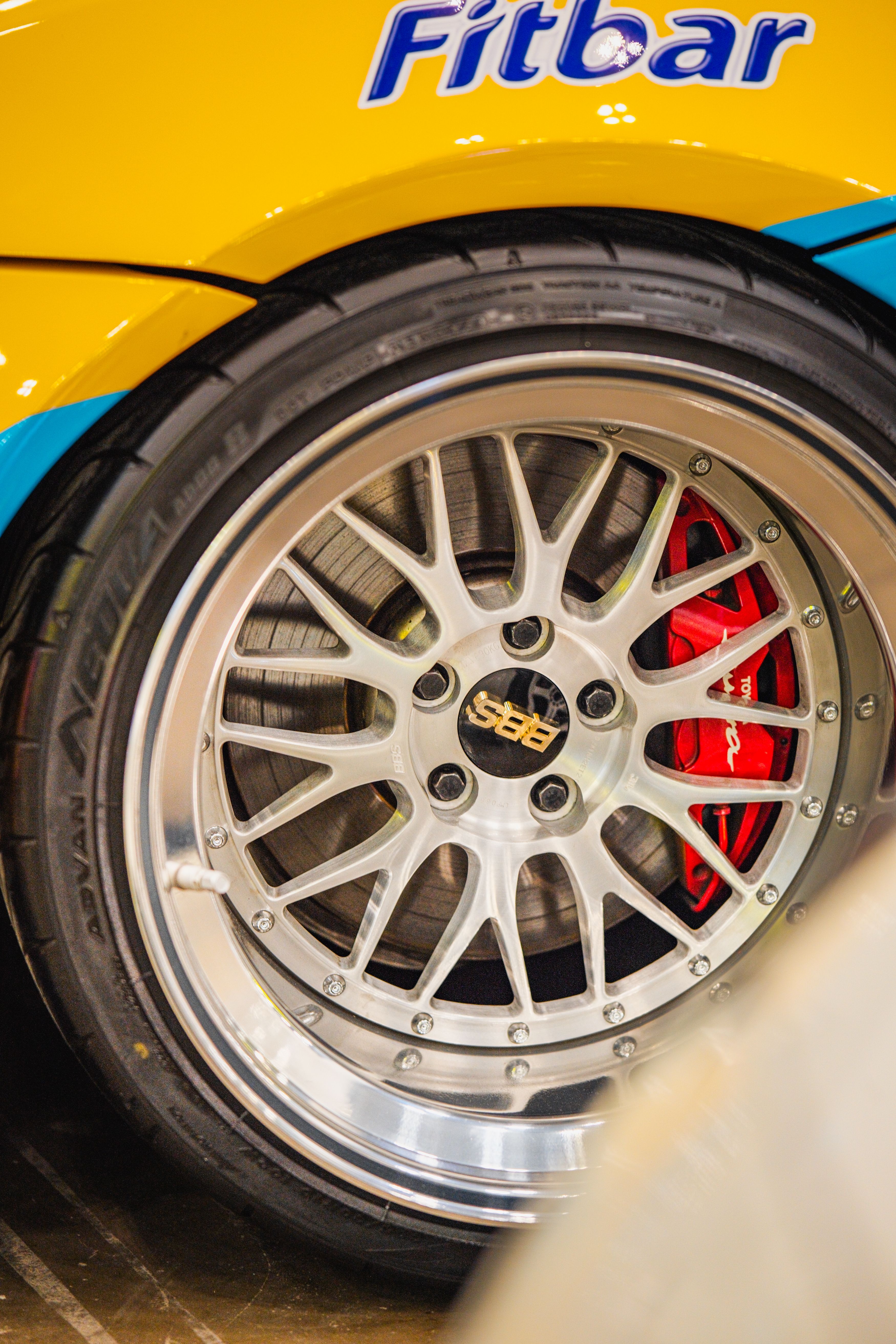 A vibrant yellow sports car featuring a custom alloy wheel and shiny brake calipers, highlighting car modification style.