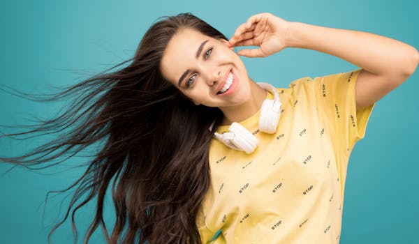 一位长发飘逸的女人戴着耳机，在碧绿色的背景下微笑