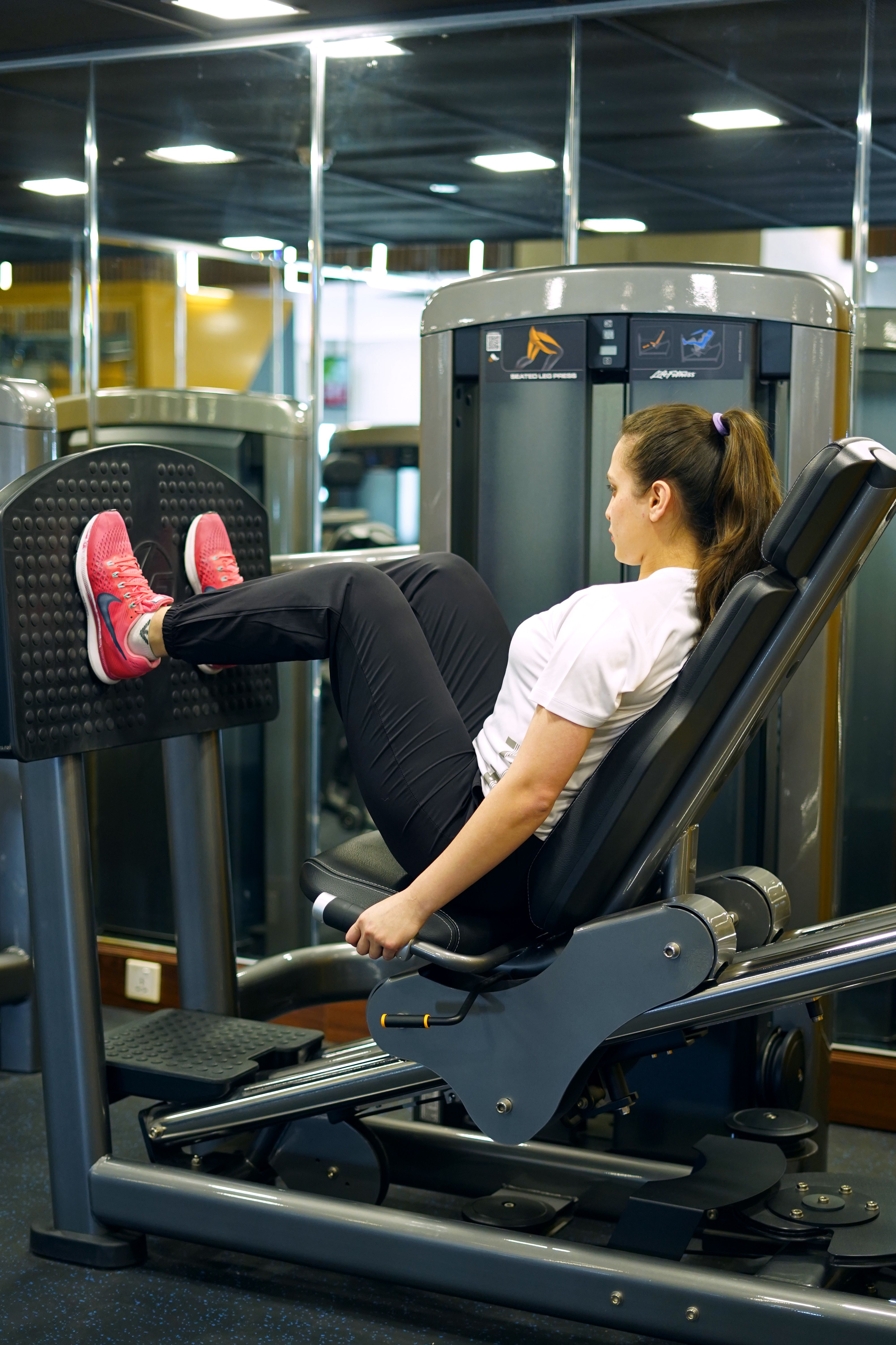 Female athlete working out on a leg press machine in a modern gym.