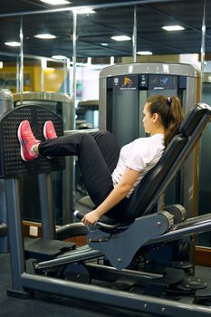 Female athlete working out on a leg press machine in a modern gym.