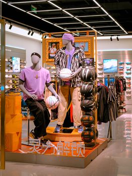 Mannequins showcasing stylish sportswear and basketballs in a modern retail store.