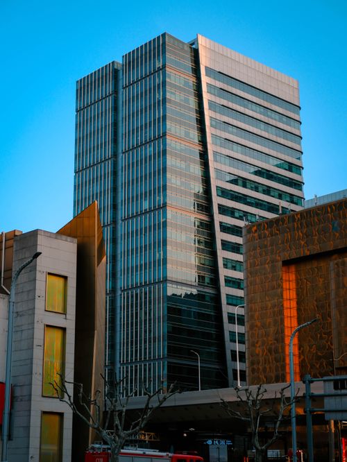 Free Tall glass skyscraper with urban architecture reflecting sunset light. Stock Photo