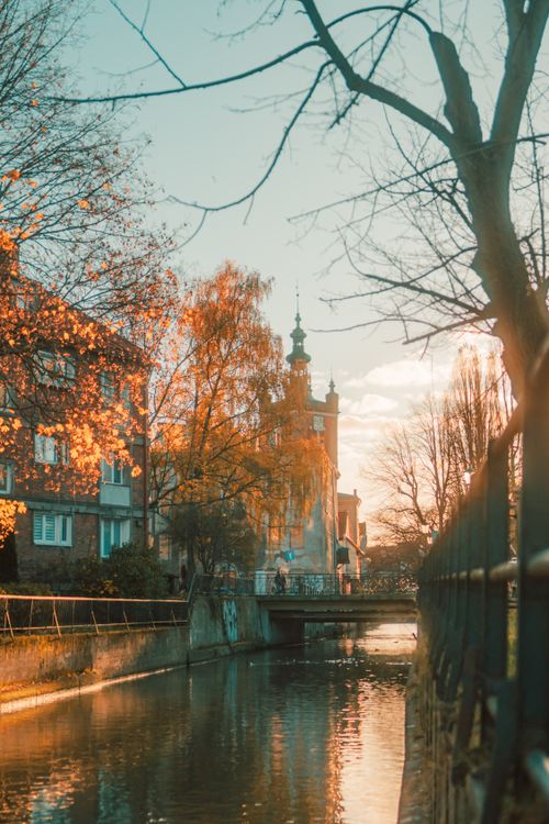 Free Picturesque autumn view of a canal with historic buildings in Gdańsk, Poland, captured during golden hour. Stock Photo