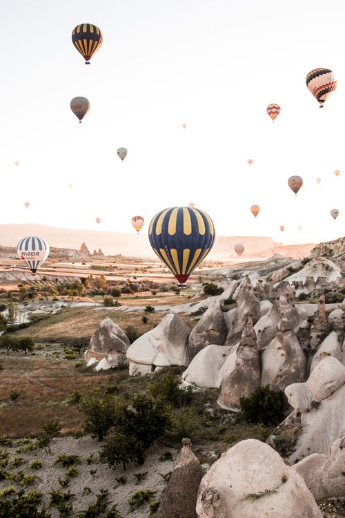 Free Stunning view of hot air balloons soaring over Cappadocia's unique rock formations during sunrise. Stock Photo