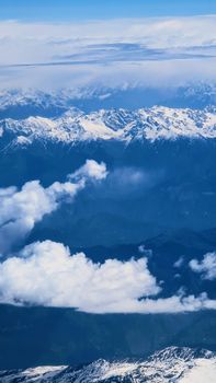 Stunning aerial view of snow-capped mountains and clouds creating a breathtaking winter landscape.