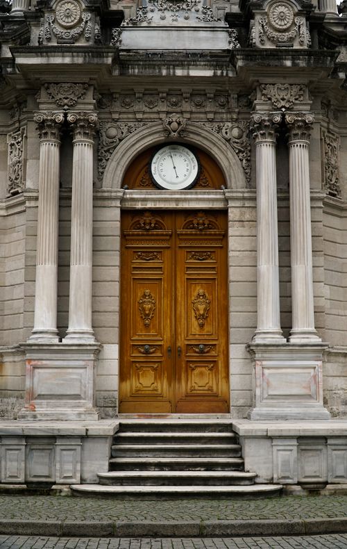 Free Elegant wooden door with intricate carvings on a historical building facade featuring classical columns. Stock Photo