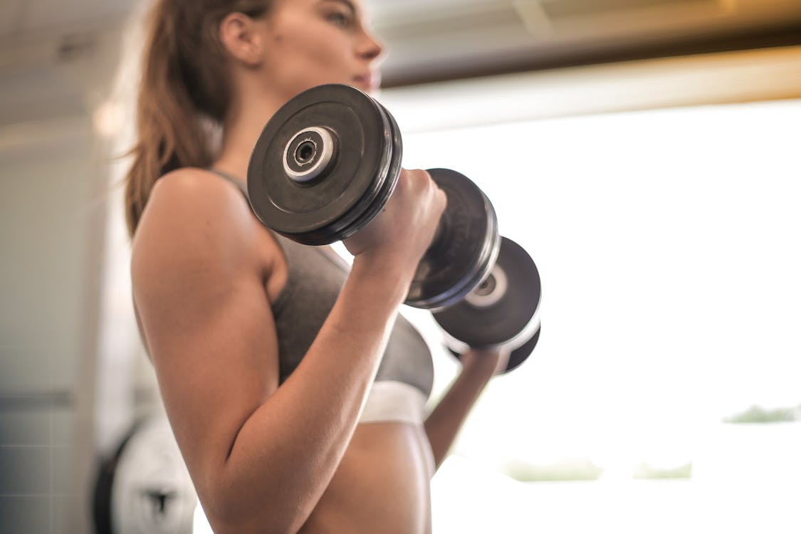 Free Woman in Gray Sports Bra Holding Black Dumbbell Stock Photo