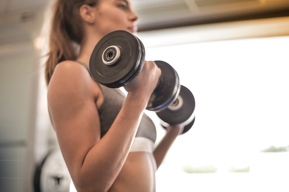 Woman in Gray Sports Bra Holding Black Dumbbells