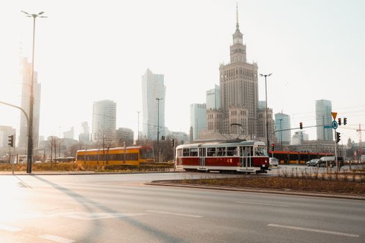 Historic tram passing through Warsaw's urban landscape with famous skyscrapers and the Palace of Culture and Science.