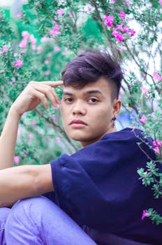 一位时尚的年轻人在开满粉色鲜花的花园里摆着姿势