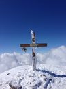 Simple wooden Christian cross with epitaph on grave covered with thick layer of snow and placed on hilltop on winter day