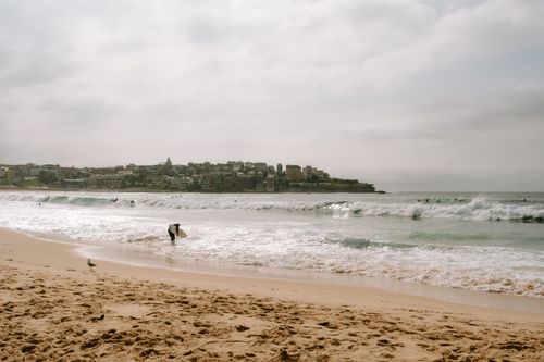 Free Surfers enjoy the waves at Bondi Beach, Sydney, showcasing a vibrant seaside scene. Stock Photo