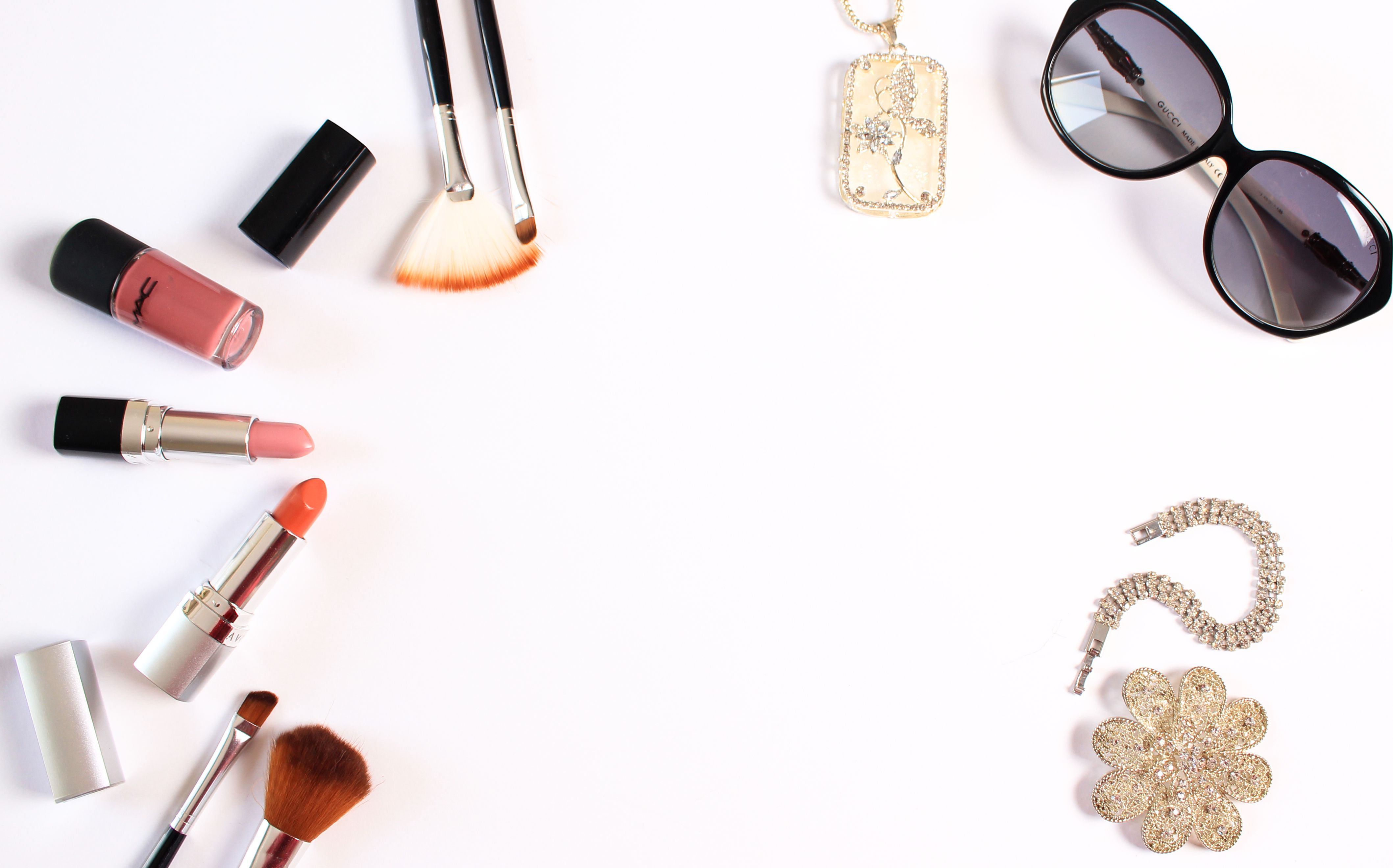 Stylish flat lay of makeup brushes, lipsticks, and glam accessories on a white background.