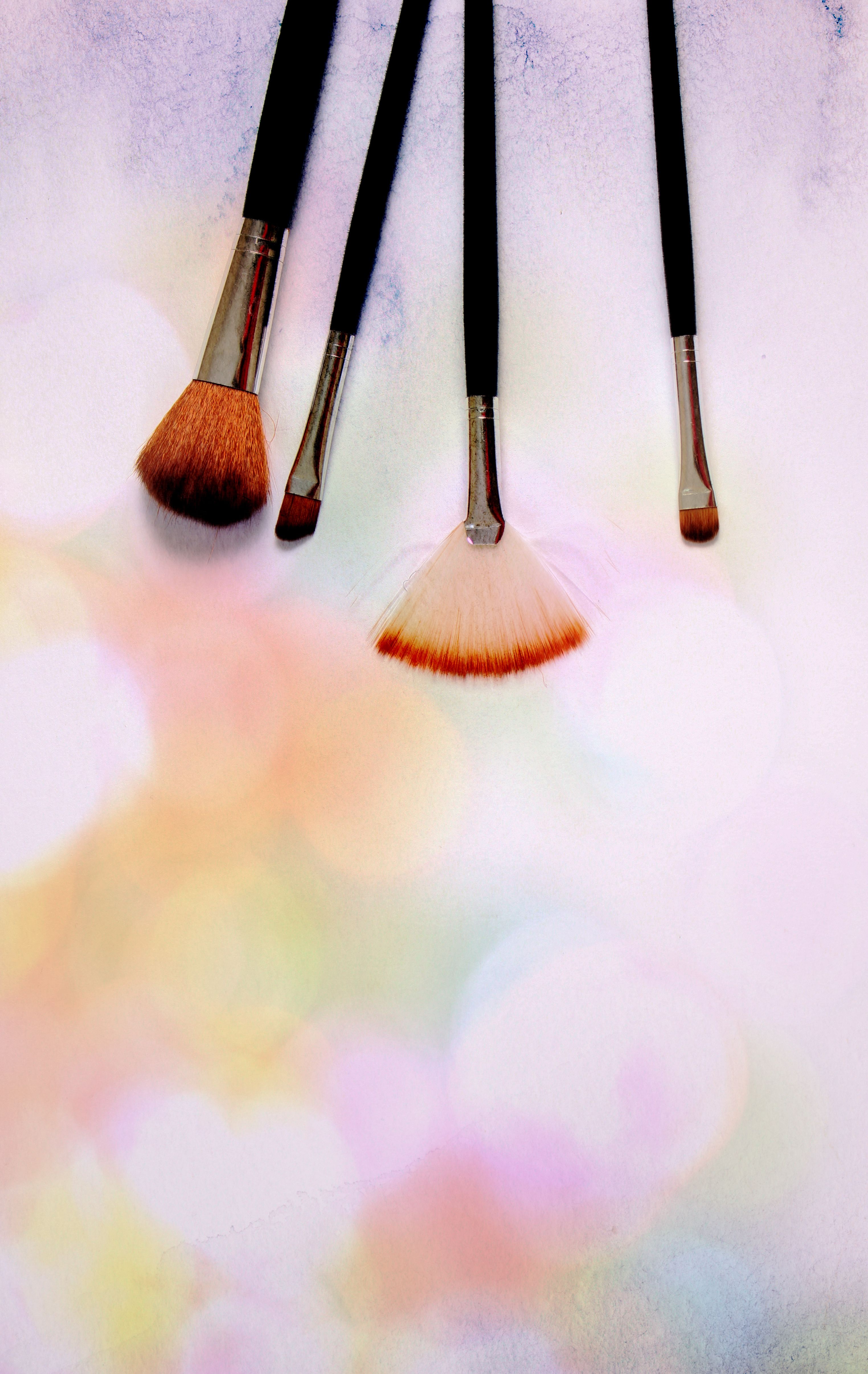Artistic display of makeup brushes against a colorful bokeh background, showcasing beauty essentials.
