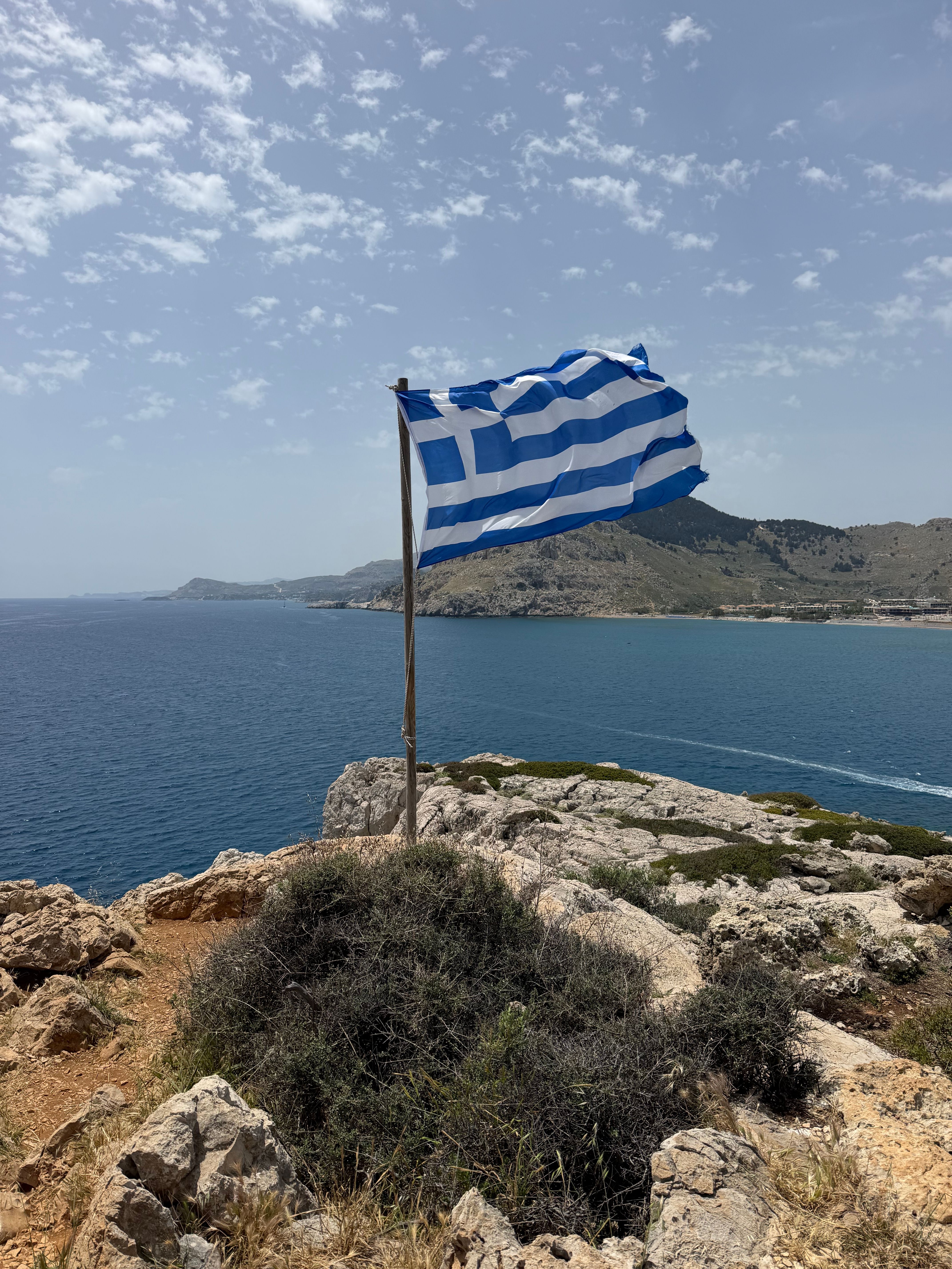 Greek Flag Waving on Rocky Rhodes Coastline · Free Stock Photo