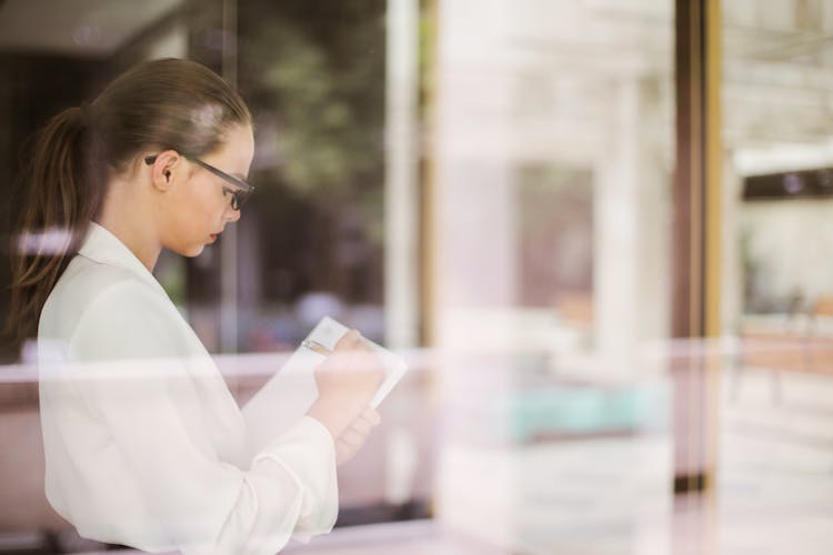 Serious Female Entrepreneur Taking Notes In Notebook