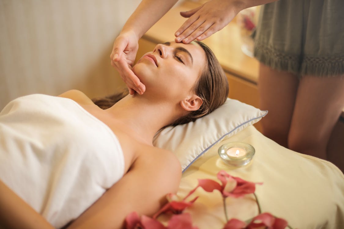 Free Woman in Wrapped in White Towel Lying on Bed Getting Massage Stock Photo