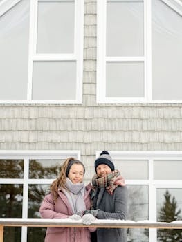 一对穿着温暖的夫妇站在时尚的小屋外，享受着冬日时光