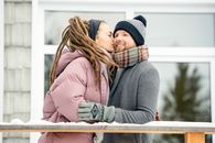 一对夫妇在冬日舒适的户外环境中，分享了一个温暖的吻