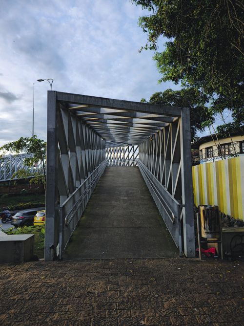 Free View of a modern pedestrian bridge in Bucaramanga, Colombia, featuring steel beams and lush surroundings. Stock Photo