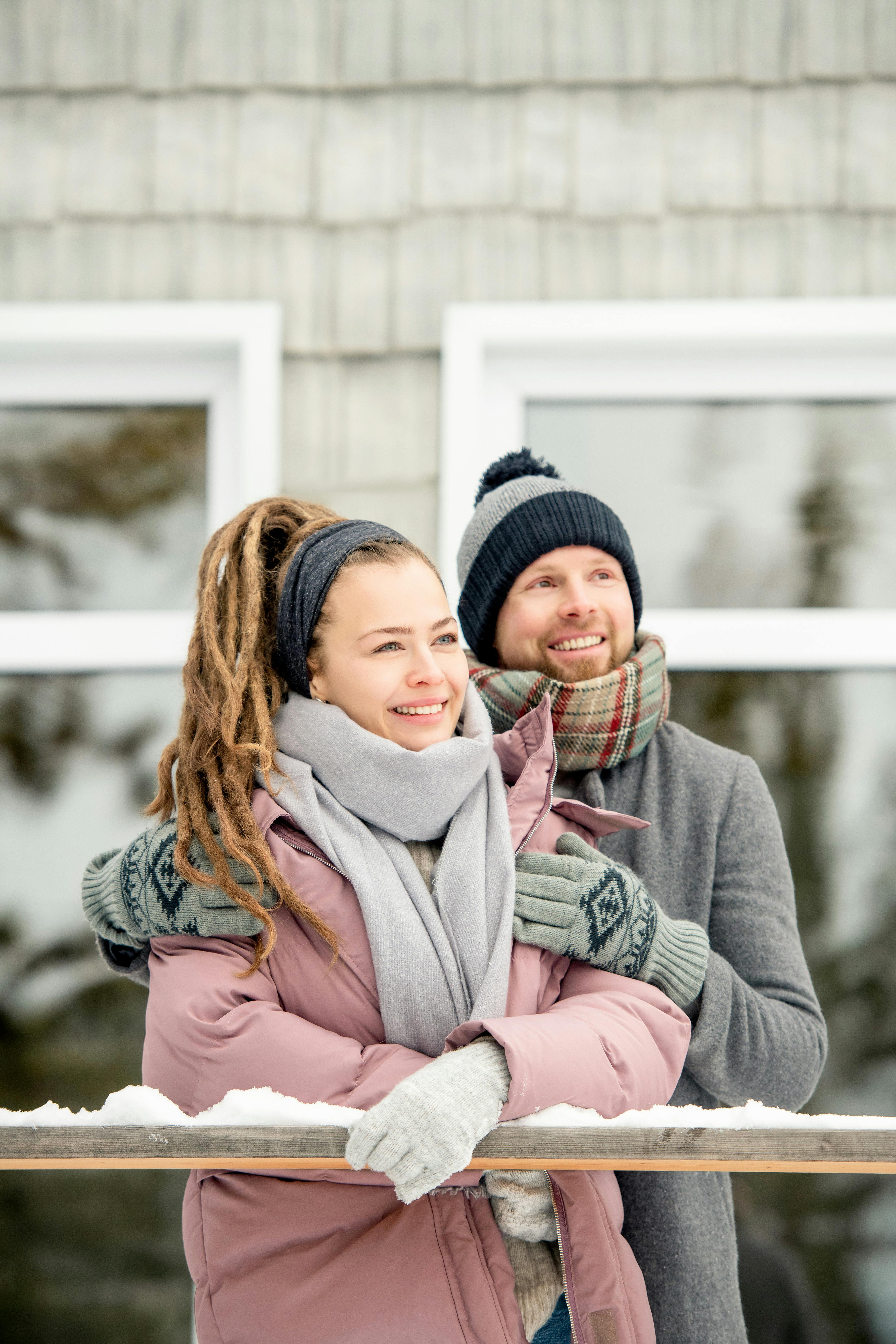 一对情侣穿着保暖的衣服，在白雪皑皑的冬日里微笑着享受户外时光