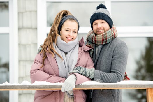 一对夫妇微笑着，在户外戴着围巾、穿着温暖的冬装，一起享受冬天