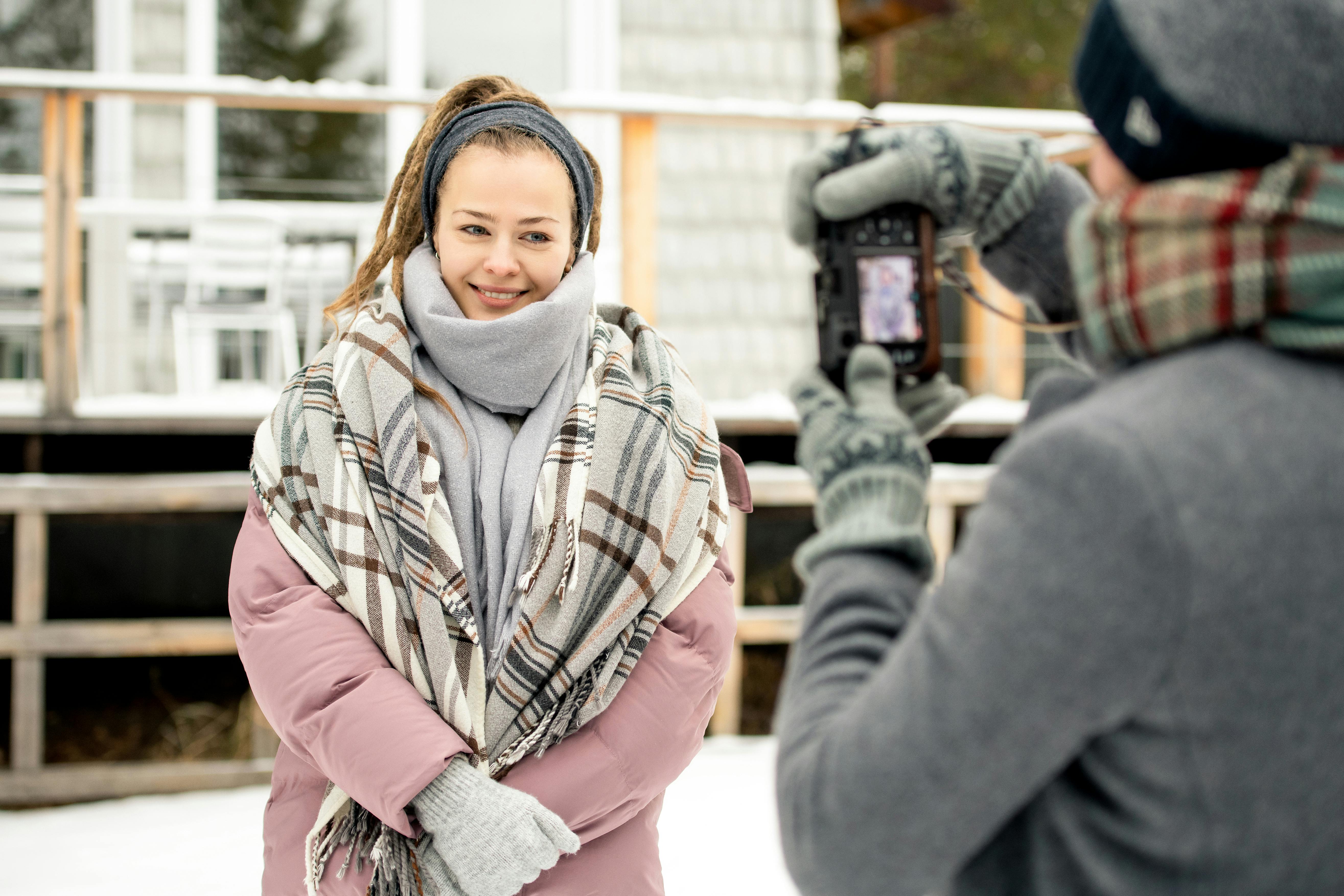 冬季户外肖像中，一位微笑的女性正在拍照