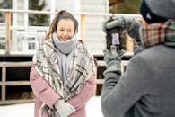 冬季户外肖像中，一位微笑的女性正在拍照