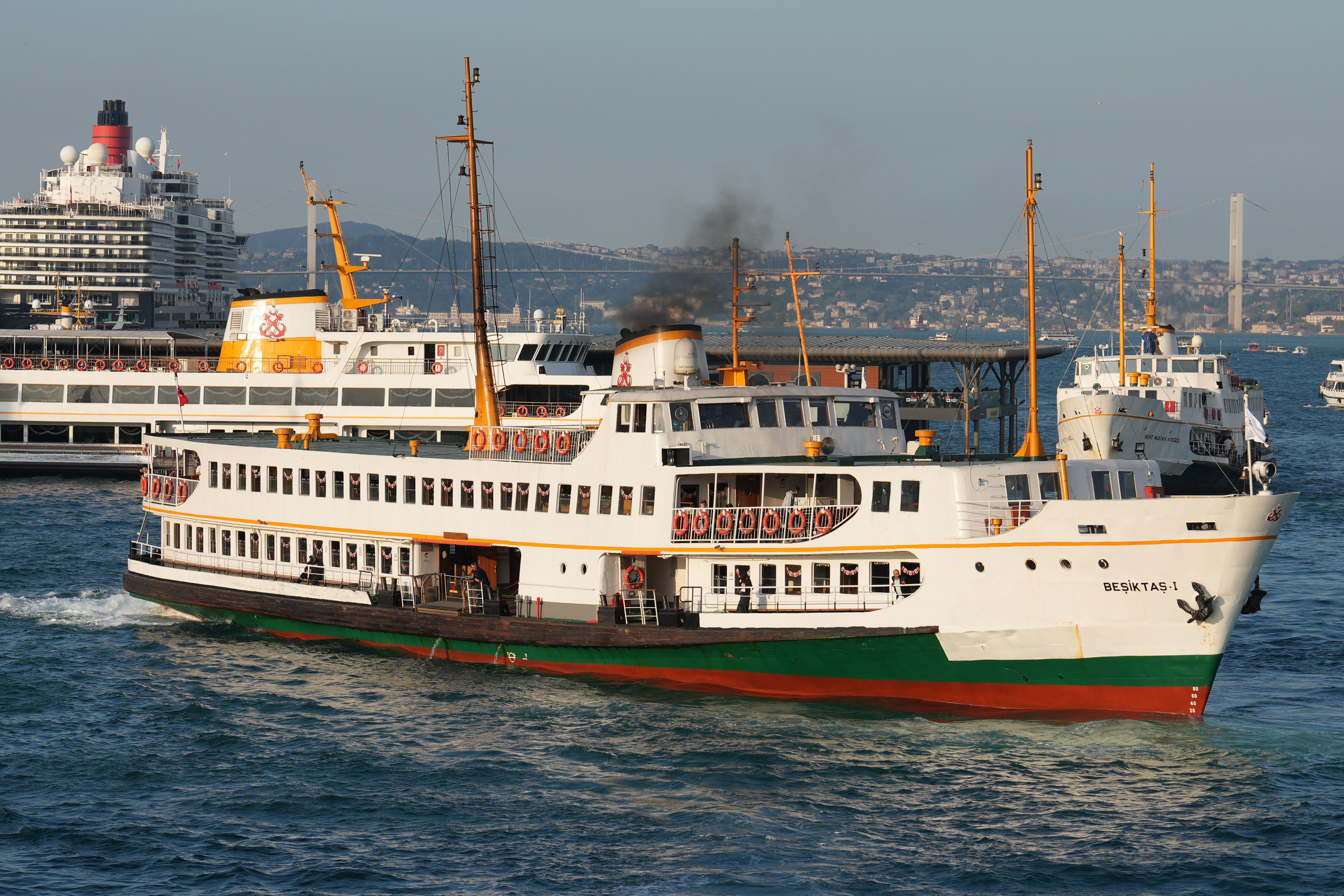 Ferries traverse the Bosphorus strait in Istanbul on a bright day with cityscape in the background.