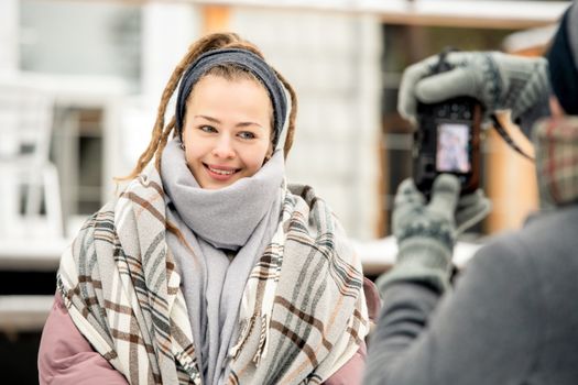一位穿着舒适冬季服装的女人在外面微笑着拍照