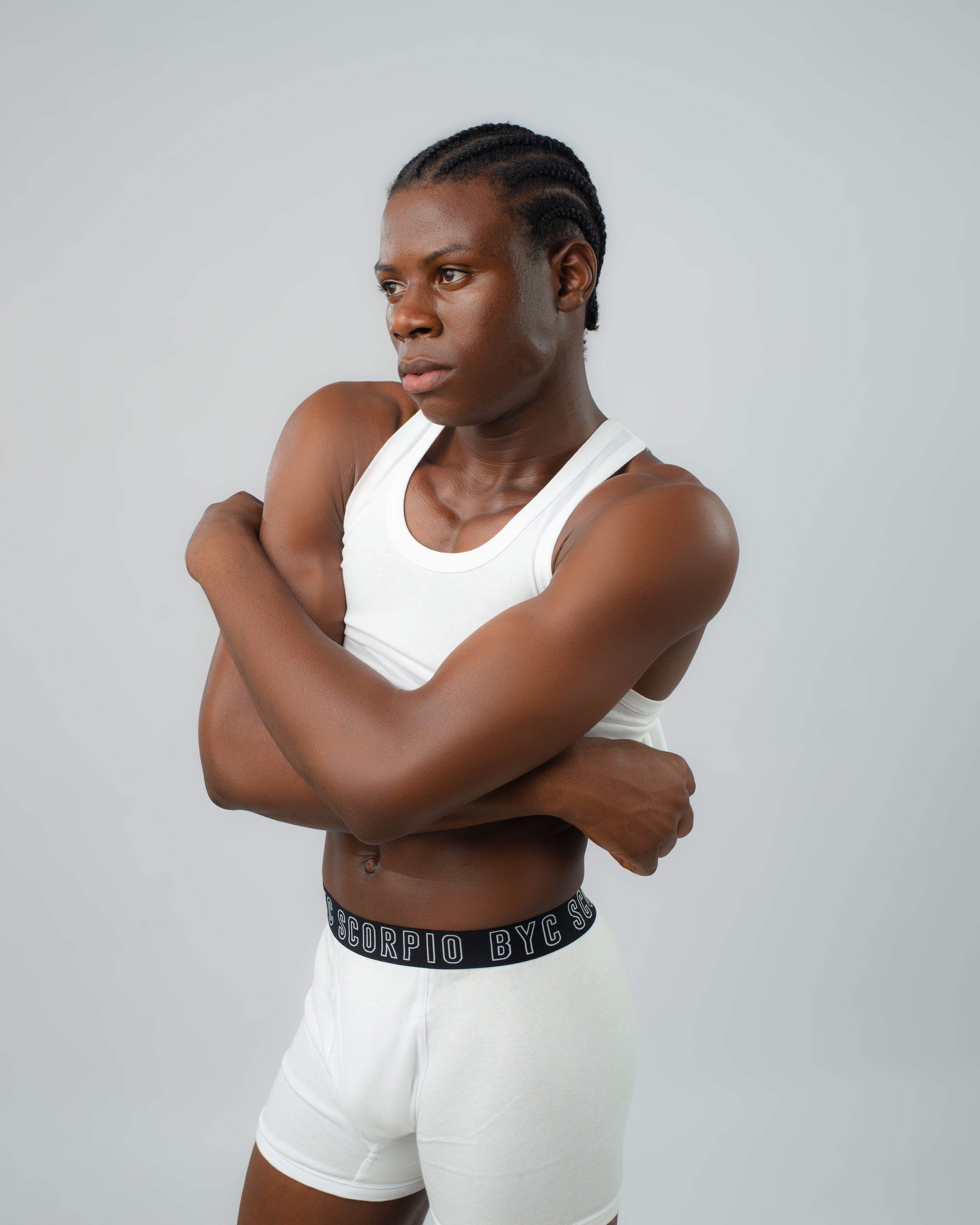 Confident young male model in white outfit posing against a neutral background.